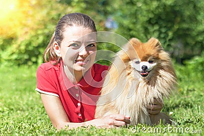 Happy girl with spitz lying on grass, looking at camera. day in life of senior, adult, elderly dog with owner. pet adoption. Stock Photo