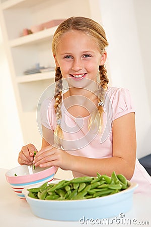 Happy girl splitting peas in kitchen Stock Photo