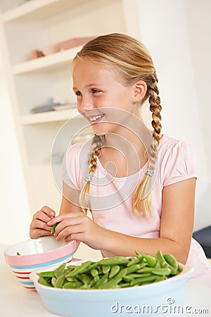 Happy girl splitting peas in kitchen Stock Photo