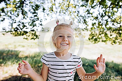 Happy girl in a striped dress smiles, shows teeth and looks at the camera Stock Photo