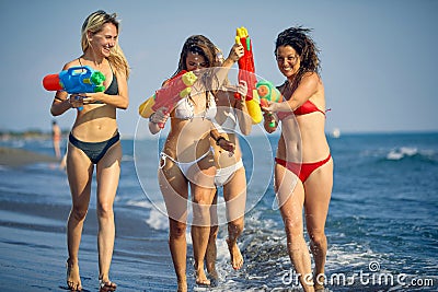 Happy girl with water guns have fun on the beach at sea Stock Photo
