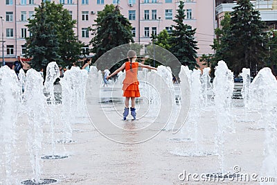 Happy girl in wet dress roller skates in fountain in summ Stock Photo