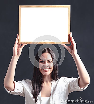 Happy girl in white shirt with poster in frame overhead. Smiling woman holding blank billboard Stock Photo