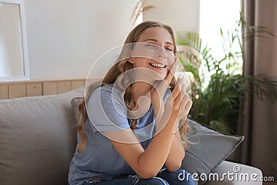 Happy girlfriend looks at engagement ring after proposal sitting on a couch in the living room at home Stock Photo