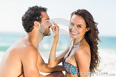 Happy girlfriend putting sunscreen on boyfriends nose Stock Photo