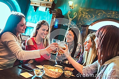 Happy girlfriends toasting beer at brewery bar restaurant - Female friendship concept with young women having genuine fun together Stock Photo