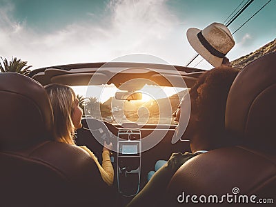 Happy girls doing road trip in tropical city - Travel people having fun driving in trendy convertible car discovering new places Stock Photo