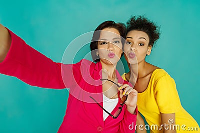 Two girlfriends blowing kisses at azur studio background Stock Photo