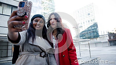 Happy girls taking a photo surprised outdoors Stock Photo