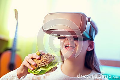 Happy girls in virtual reality glasses eating sandwich Stock Photo