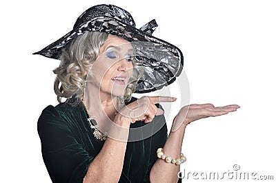 Happy gorgeous mature woman in hat showing something Stock Photo