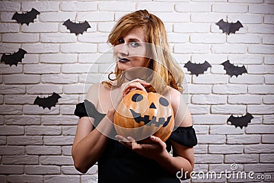 Happy gothic young woman with creepy makeup and pumpkin in hands Stock Photo