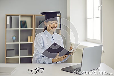 Happy graduate sitting at laptop computer and presenting her thesis remotely via video call Stock Photo