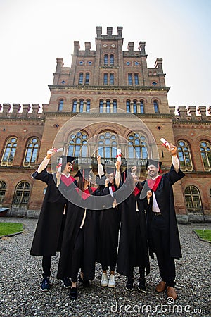 Happy graduates. Five college graduates standing in a row and smiling Stock Photo