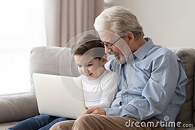 Happy grandfather and cute little grandson using laptop together Stock Photo