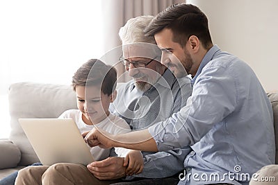 Happy grandfather and father teaching little boy to use laptop Stock Photo