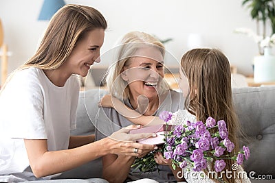 Happy grandma thanking grandchild and grown daughter for flowers Stock Photo