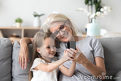 Happy grandmother and cute granddaughter using cellphone making Stock Photo