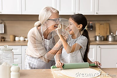 Happy grandmother and granddaughter touching faces with floury hands Stock Photo