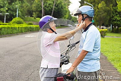 Happy grandmother help grandfather to wear a helmet Stock Photo