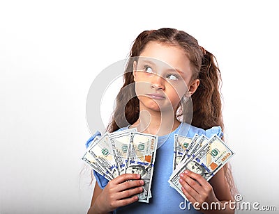 Happy grimacing thinking kid girl holding money in the hands and Stock Photo