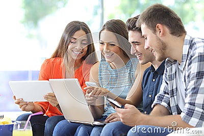 Happy group of friends checking multiple devices Stock Photo