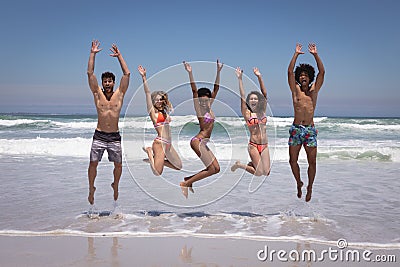 Happy group of friends jumping together on beach in the sunshine Stock Photo