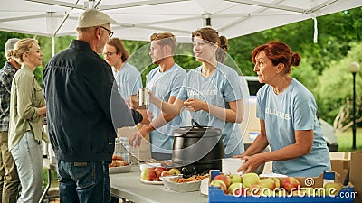 Happy Group of Young Adult Volunteers Serving Free Food for Poor People in Need. Charity Workers Stock Photo
