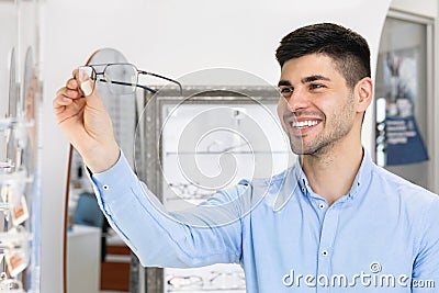 Happy guy choosing glasses at optics store Stock Photo