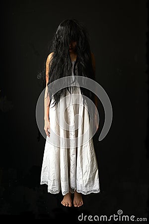 Scary ghost woman. Asian ghost or zombie horror creepy scary have hair covering face and eye reach arm out at abandoned house. Stock Photo