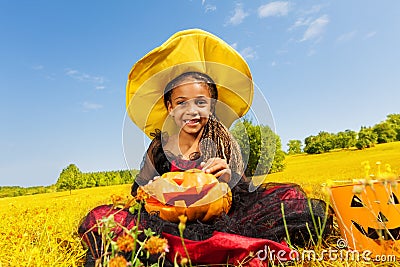 Happy Halloween girl sitting on yellow grass Stock Photo