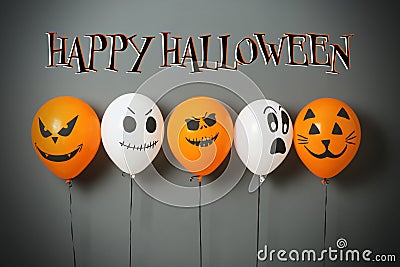 Happy Halloween greeting card. Color balloons with drawn spooky faces on grey background Stock Photo