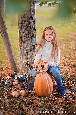 Happy Halloween! Little girl carving pumpkin at Halloween. Dressed up children trick or treating. Kids trick or treat. Toddler kid Stock Photo