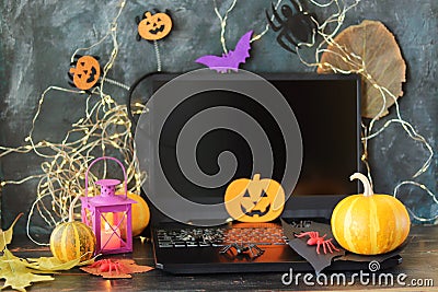 Happy Halloween, pumpkins, scary face carved on autumn leaves, mystical decor and a lantern with a burning candle, laptop on a bla Stock Photo