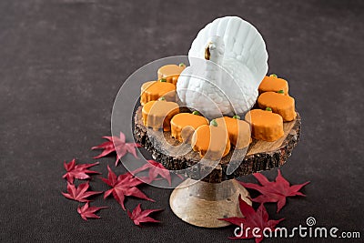 Happy Halloween, small pumpkin cakes, orange ceramic pumpkin on a wooden cake stand, plastic skeleton Stock Photo