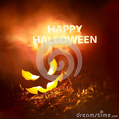 Happy Halloween text glowing in red and yellow smoke at night above a creepy pumpkin Jack o` Lantern Stock Photo