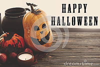 Happy Halloween text sign on pumpkins, jack-o-lantern, witch cauldron, bats, spider, candle, autumn leaves on black wood in light Stock Photo