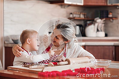 A happy handicapped down syndrome child with his mother indoors baking. Stock Photo