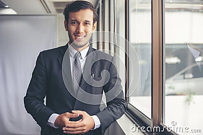 Happy handsome businessman standing and smiling in office Stock Photo