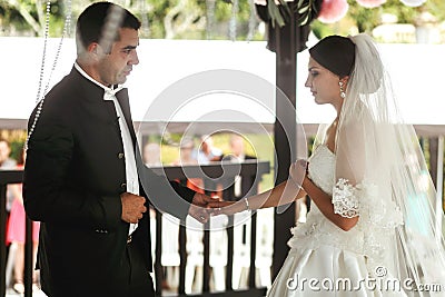 Happy handsome groom and beautiful bride in white dress in wedding arbor at ceremony Stock Photo