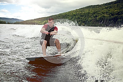 Happy handsome man wakesurfing in a lake Stock Photo