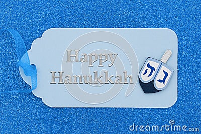 Happy Hanukkah greeting on blue holiday gift tag with a dreidel on glitter paper Stock Photo