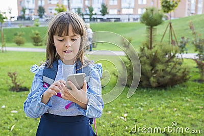 Happy high school girl on a city street playing an online game with a phone Stock Photo