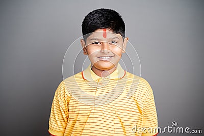 Happy Hindu kid with kumkum Bindi or Tilak on forehead by looking at camera on studio background - concept of smiling and positive Stock Photo