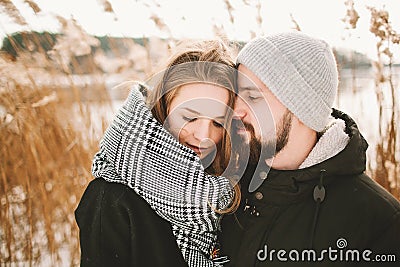 Happy hipster couple hugging near winter lake and reeds Stock Photo