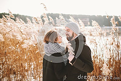 Happy hipster couple hugging near winter lake and reeds Stock Photo