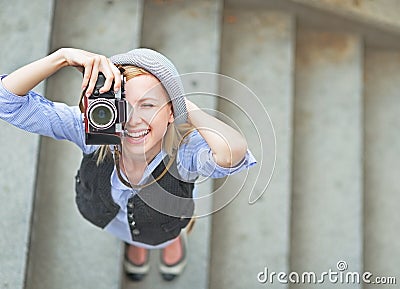 Happy hipster girl making photo with retro camera on city street Stock Photo