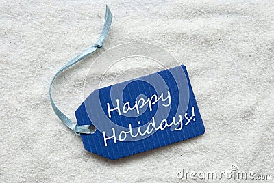 Happy Holidays On Blue Label Sand Background Stock Photo