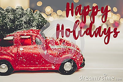 Happy holidays text, seasonal greetings card sign. red car toy w Stock Photo