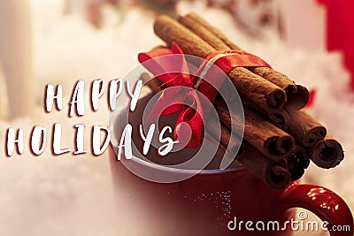 Happy holidays text sign on cinnamon sticks with ribbon on red c Stock Photo
